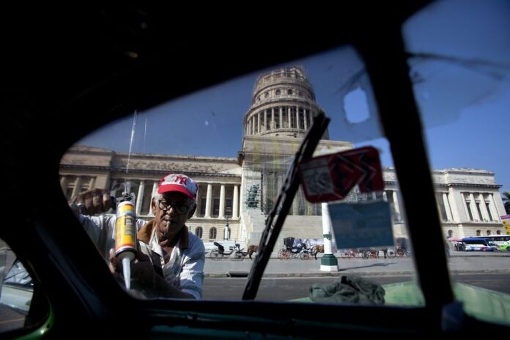 Un hombre aplica silicona en un vehículo Ford, modelo 48.