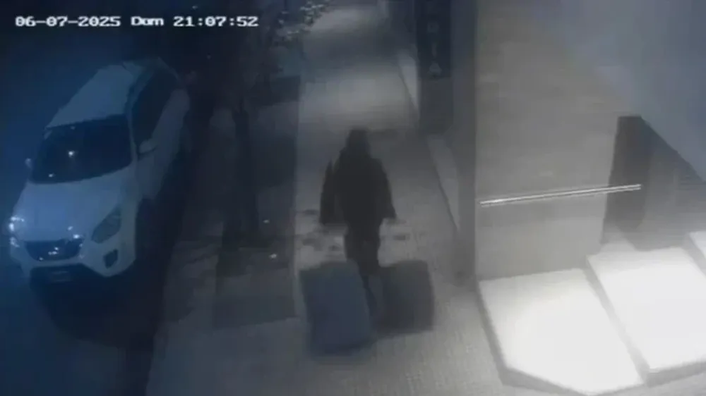 La mujer deja el edificio de una víctima con dos valijas llenas de elementos robados. (Captura de video)