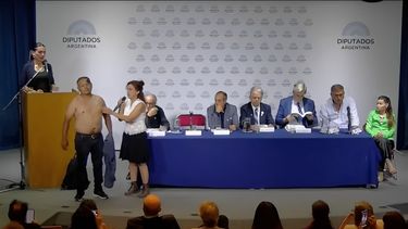 El momento en el que la disertante Lorena Diblasi comienza a apoyar objetos sobre el torso del hombre.