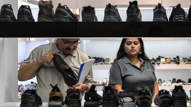 Personas observan zapatos en una tienda de calzado. (Xinhua)