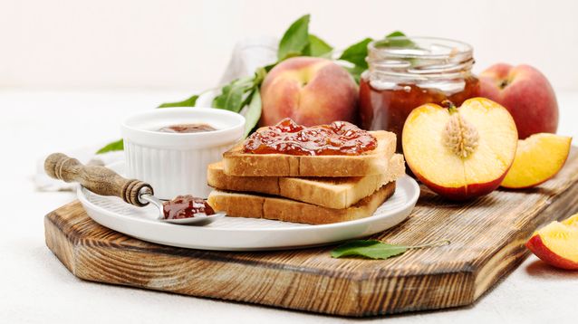 Un desayuno con pan casero y mermeladas de durazno y frutilla. ¿Qué más?