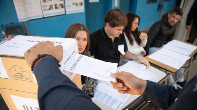 Una persona vota frente a las autoridades de mesa.