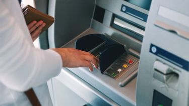 Una persona sacando dinero de un cajero.