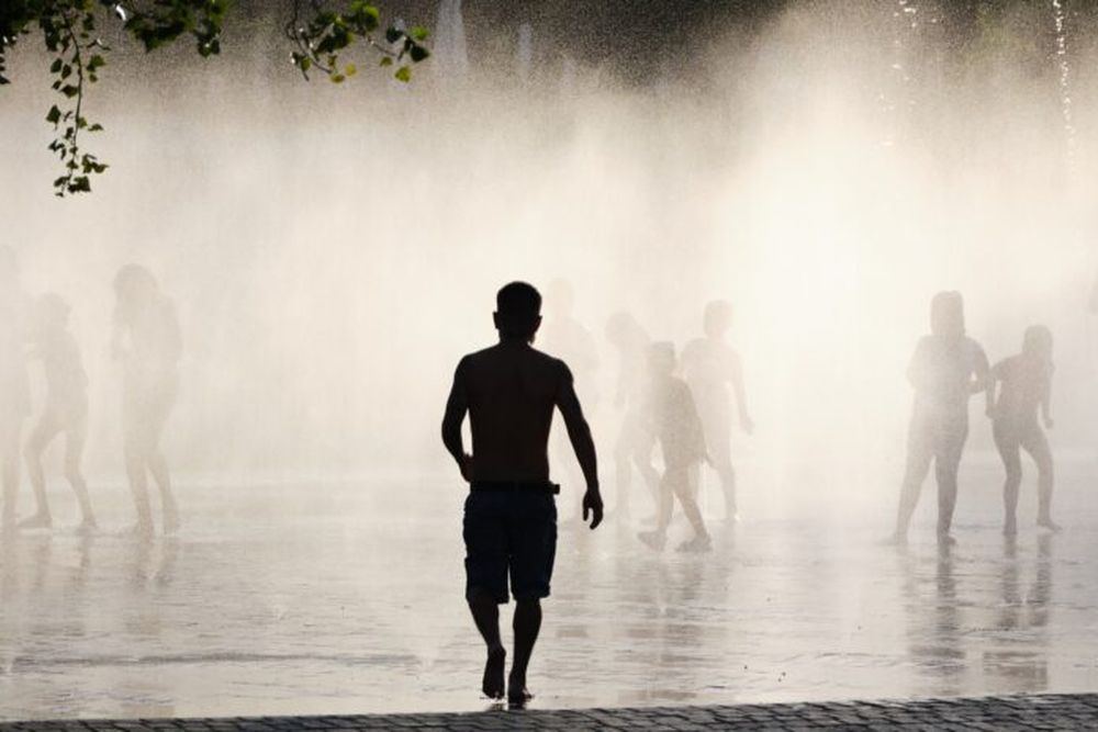 Un hombre caminando hacia una fuente para refrescarse. (Xinhua/Meng Dingbo)