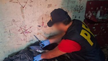 Un efectivo durante el allanamiento. En las paredes se observan graffitis de tinte satánico.