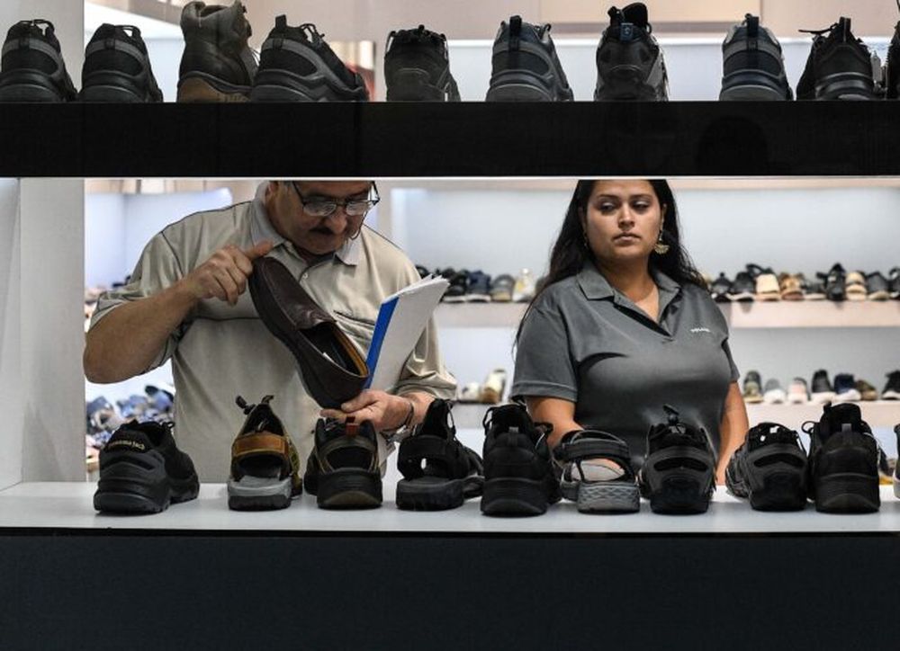 Personas observan zapatos en una tienda de calzado. (Xinhua)