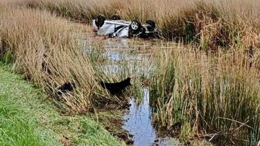 El coche quedó en la banquina llena de agua, con la ruedas hacia arriba.