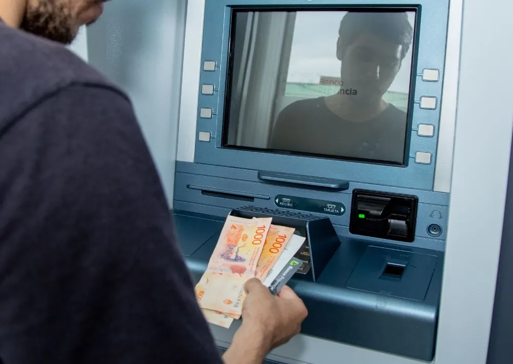 Una persona retira dinero de un cajero.&nbsp;