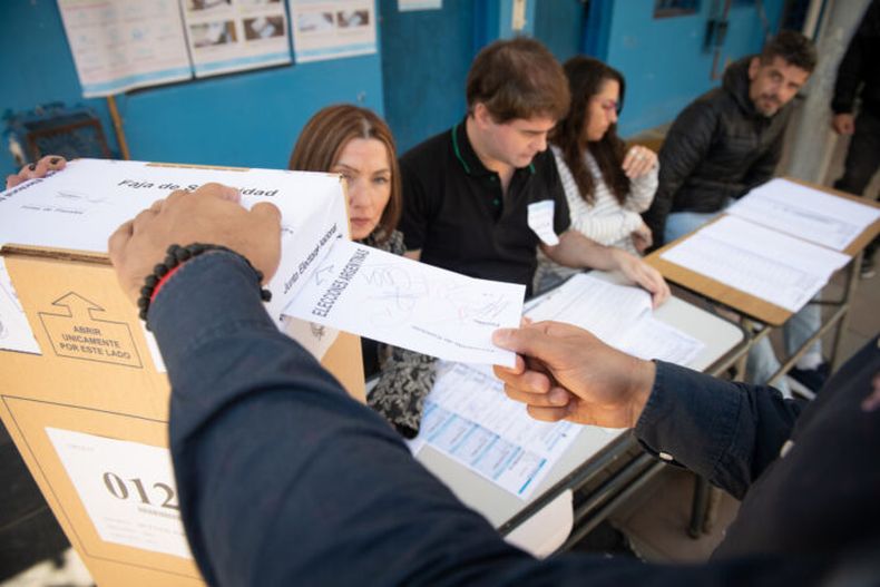 Una persona vota frente a las autoridades de mesa.