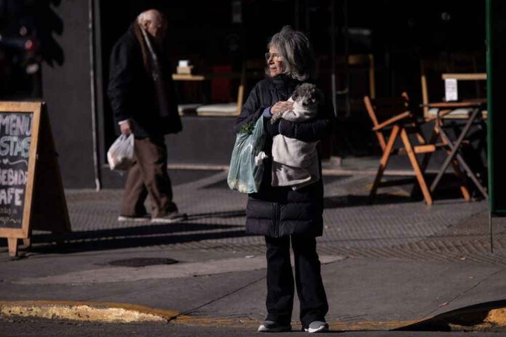 Una mujer porta ropa abrigadora mientras sostiene a su perro en brazos. (Xinhua/Martín Zabala)